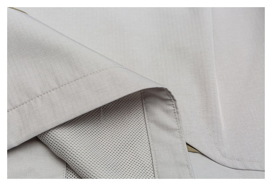 Close-up of light gray garment with a stitched seam and a mesh panel beneath a folded fabric edge.