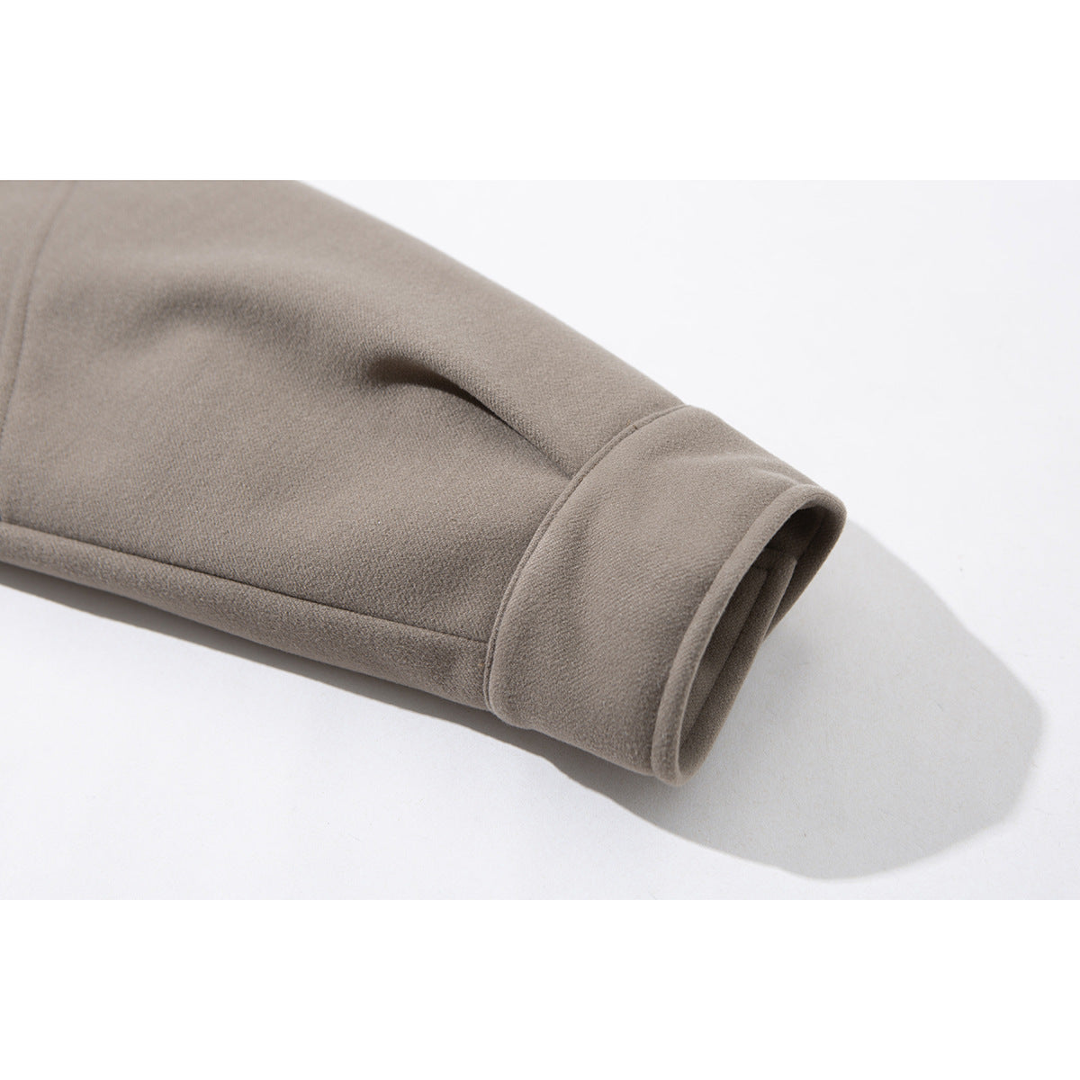 Close-up of a taupe jacket sleeve ending in a wide stitched cuff.