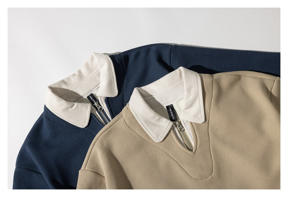 Overlapping navy and tan pullovers show their cream collars and short zip necklines.