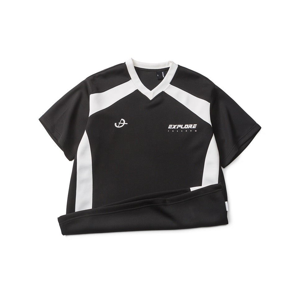 Flat-lay front view of a black short-sleeve shirt with white panels, a V-neck, and chest graphics.
