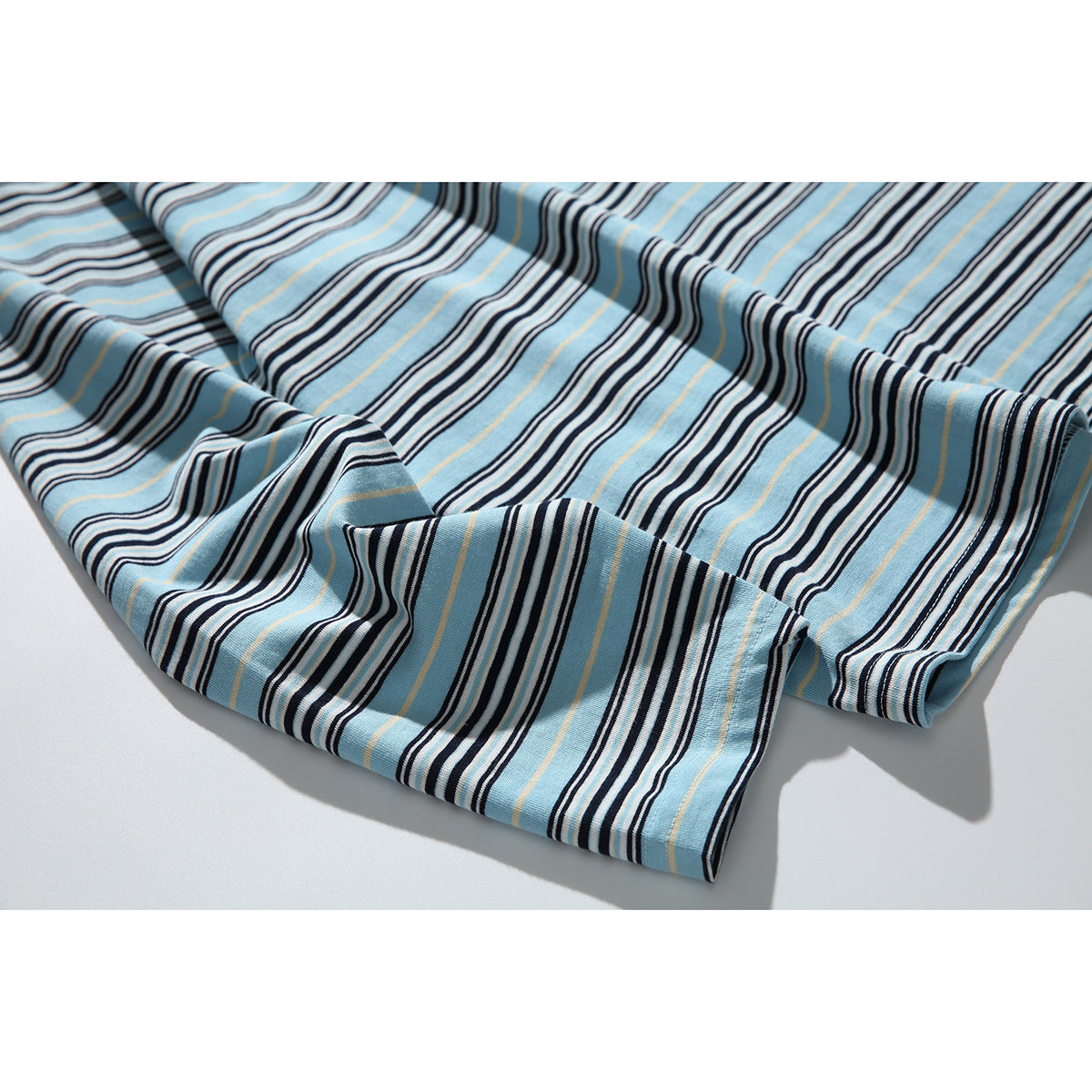 Close-up of the blue shirt’s multicolored stripes across folded fabric and a stitched edge.