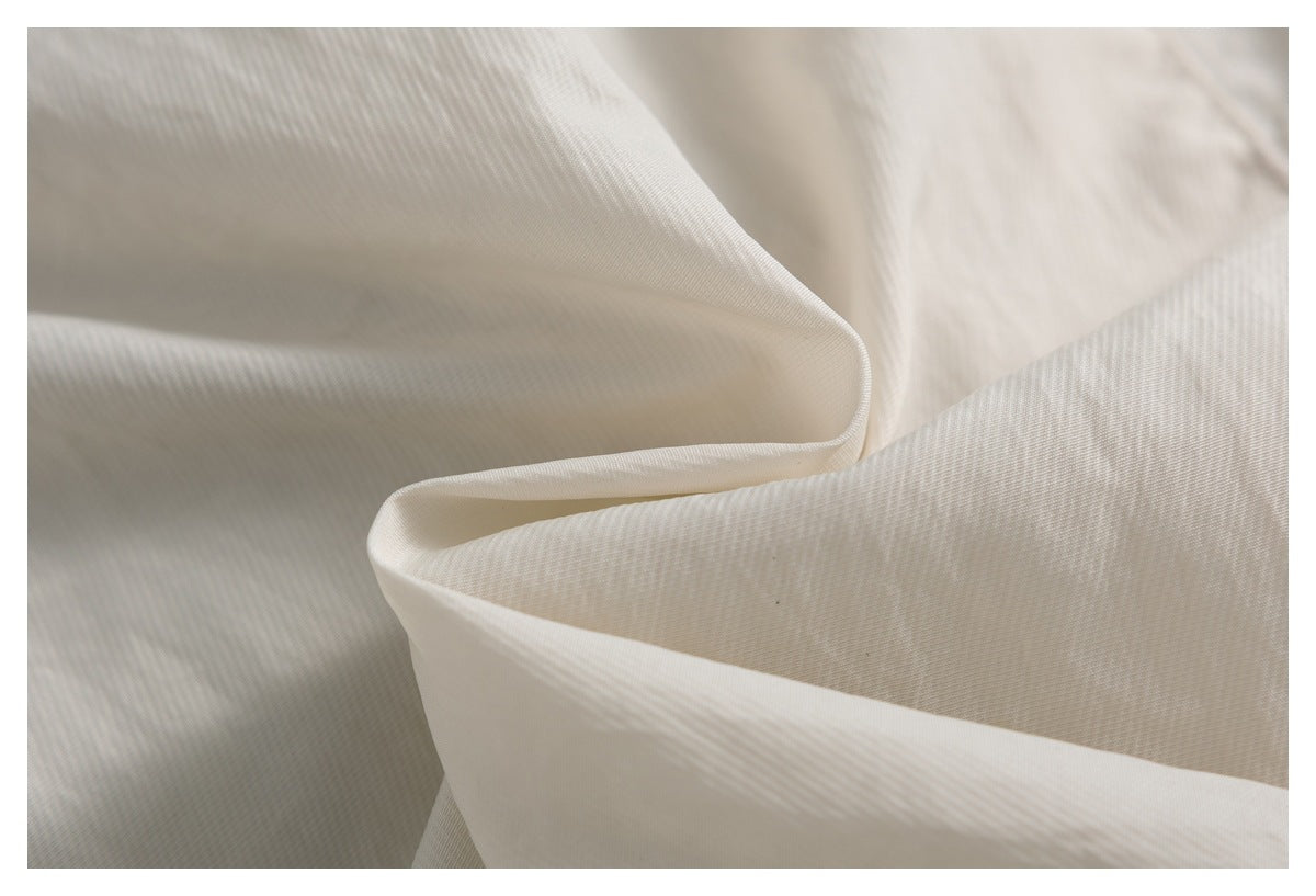 Close-up of softly folded ivory fabric showing its fine diagonal weave.
