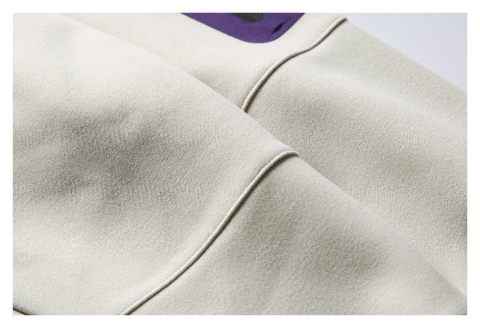 Close-up of a pale cream garment with curved seams and a small edge of purple fabric visible.