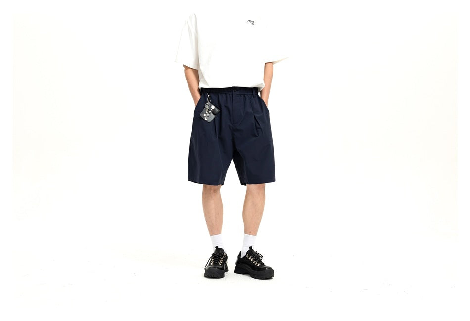 Front view of a model wearing navy knee-length shorts with a white T-shirt; the head is cropped out.