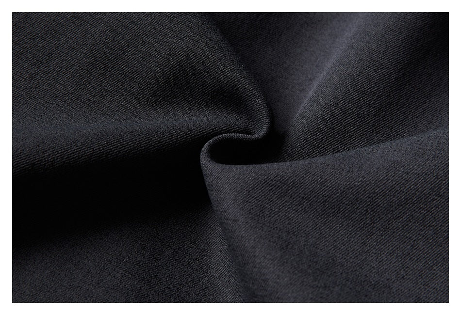 Close-up of dark charcoal-black fabric with a fine diagonal weave and soft folds.
