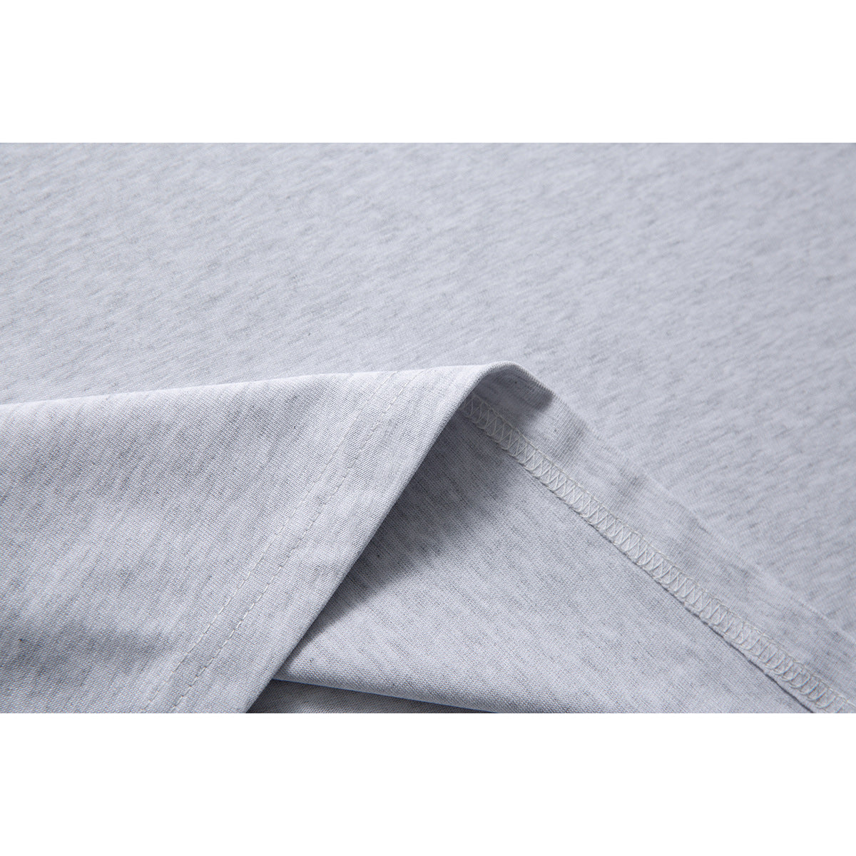 Close-up of the light gray shirt fabric and curved stitched hem seam.