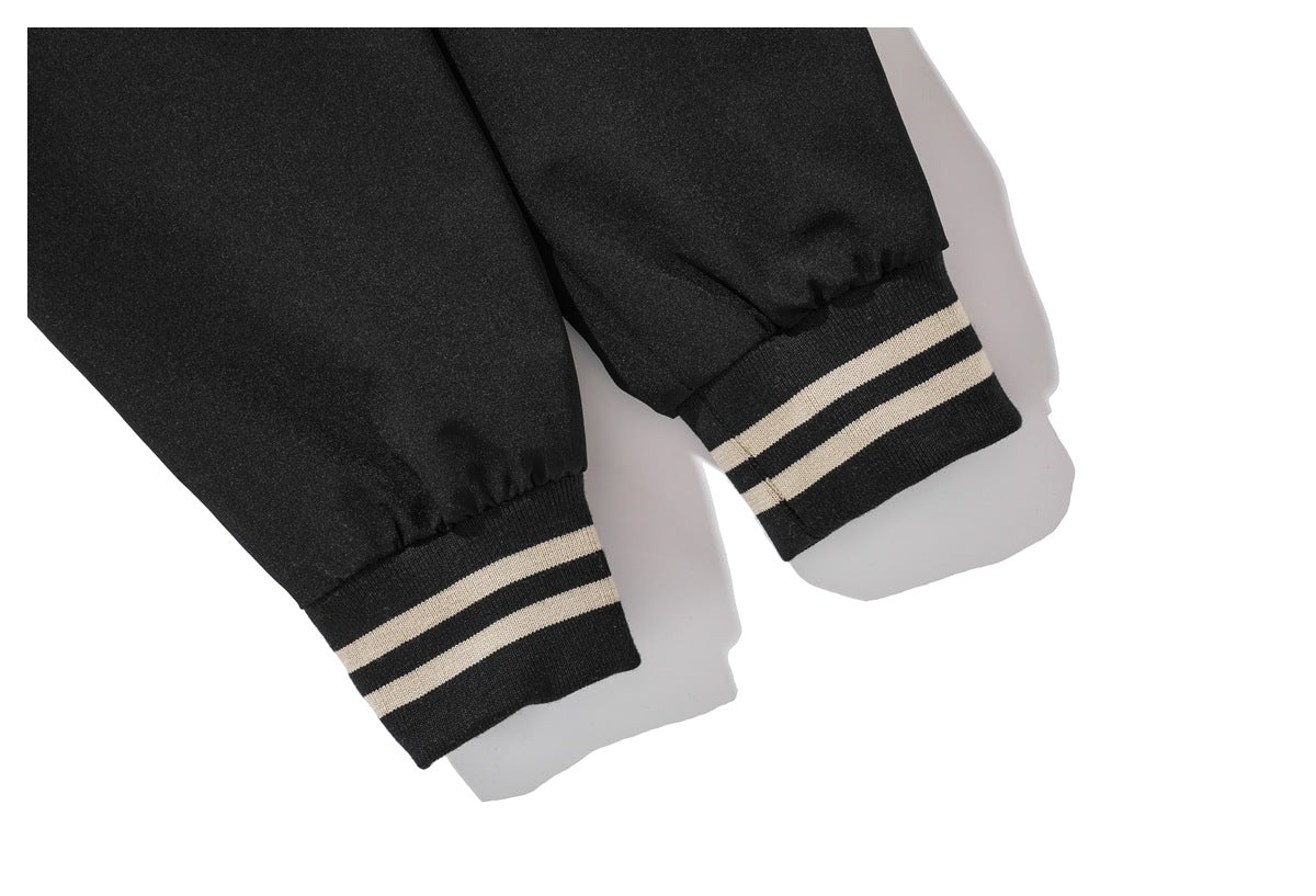 Close-up of black jacket sleeves with black ribbed cuffs featuring two cream stripes.