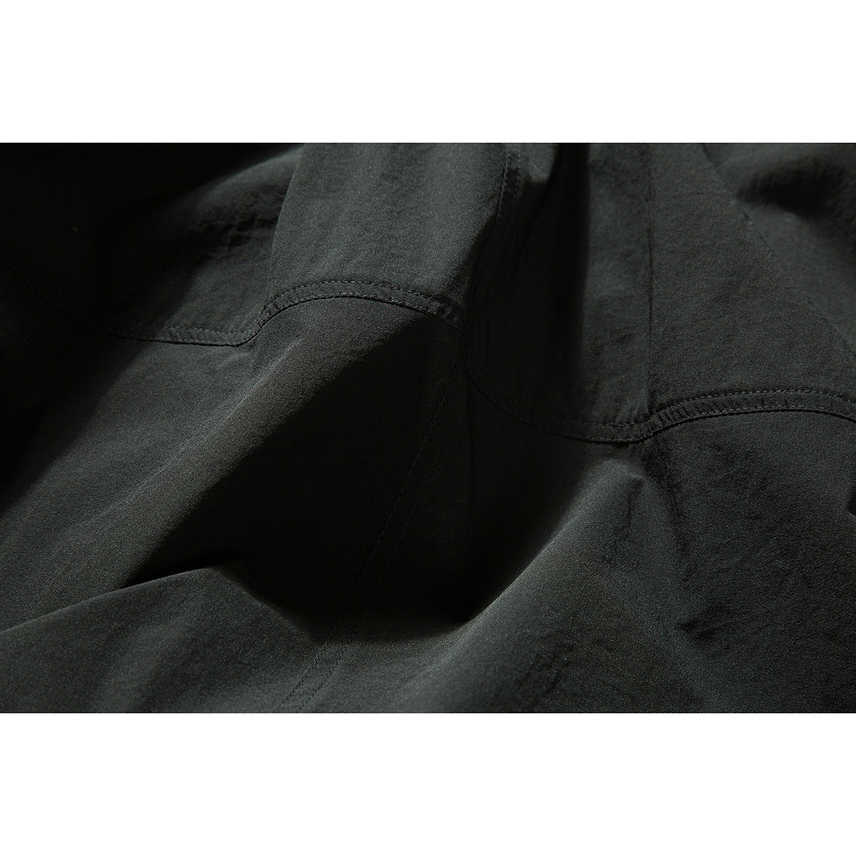 Close-up of black fabric panels with curved double-stitched seams.
