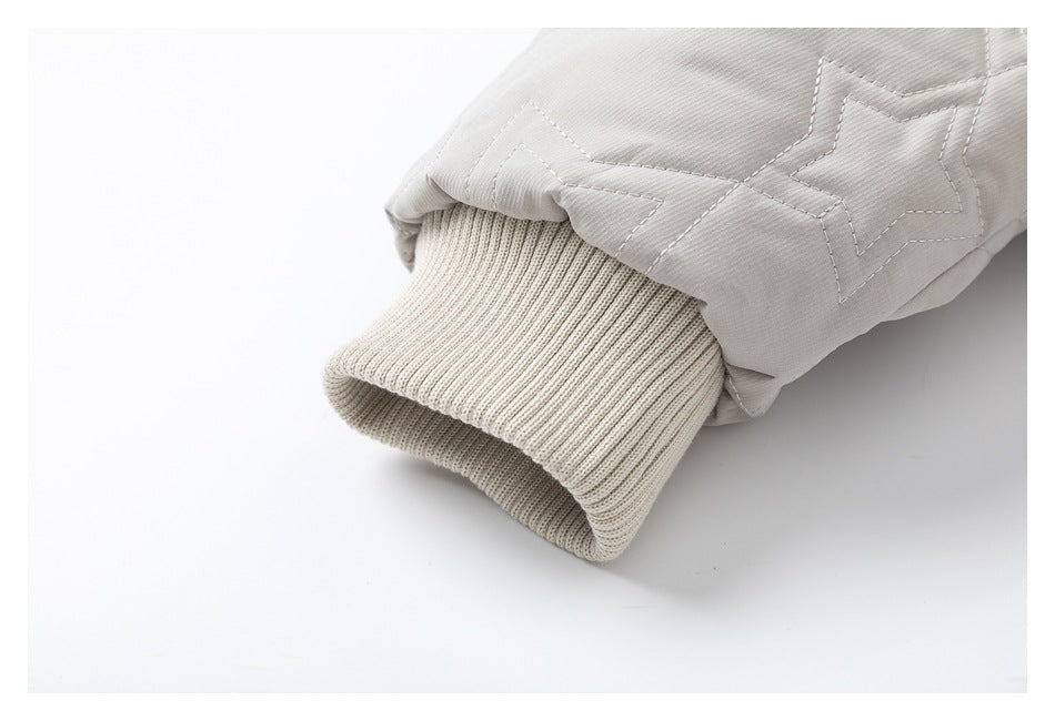 Close-up of the light gray quilted jacket's cream rib-knit sleeve cuff and star stitching.