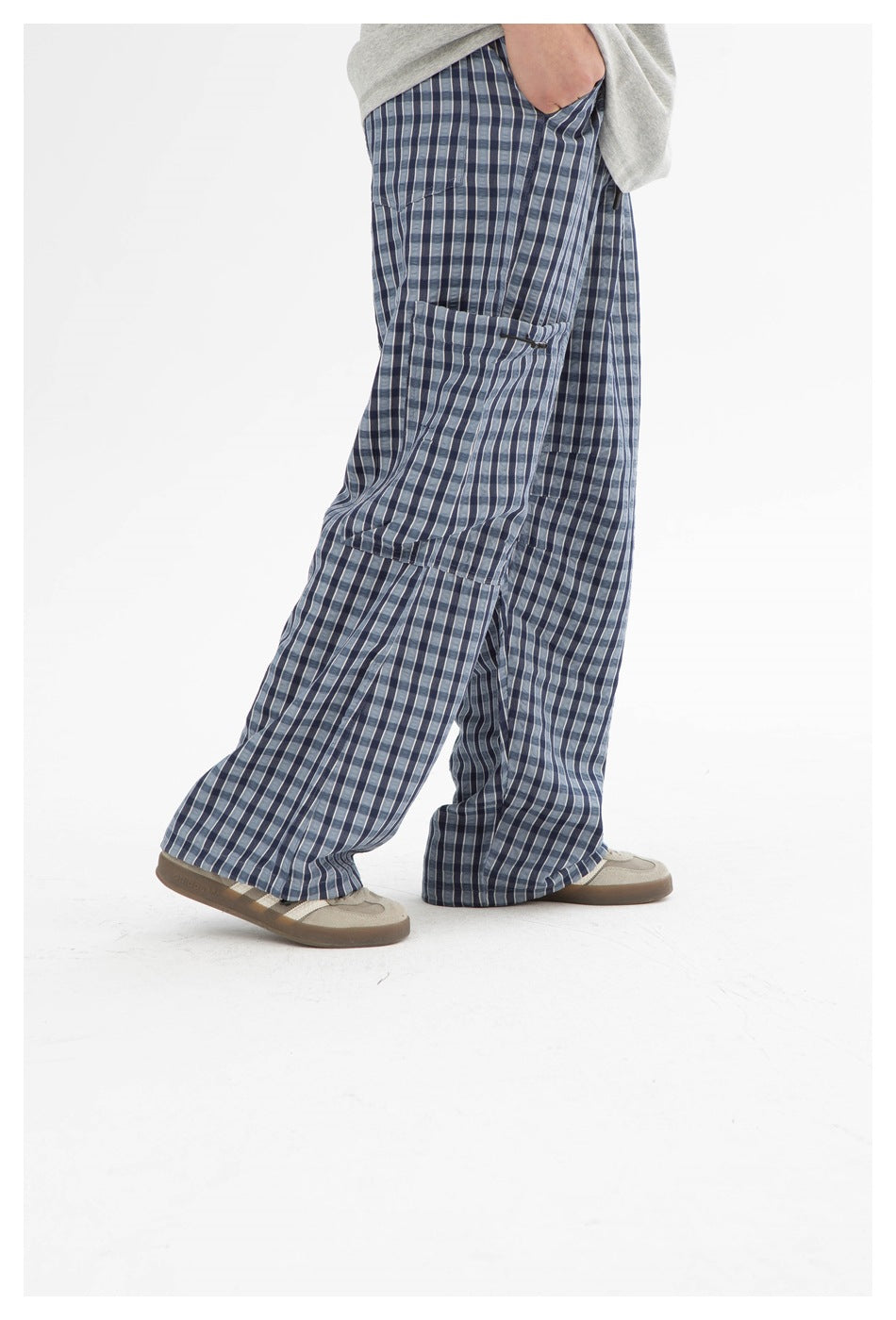Side view of loose blue plaid cargo pants worn with a gray top, highlighting the large cargo pocket.