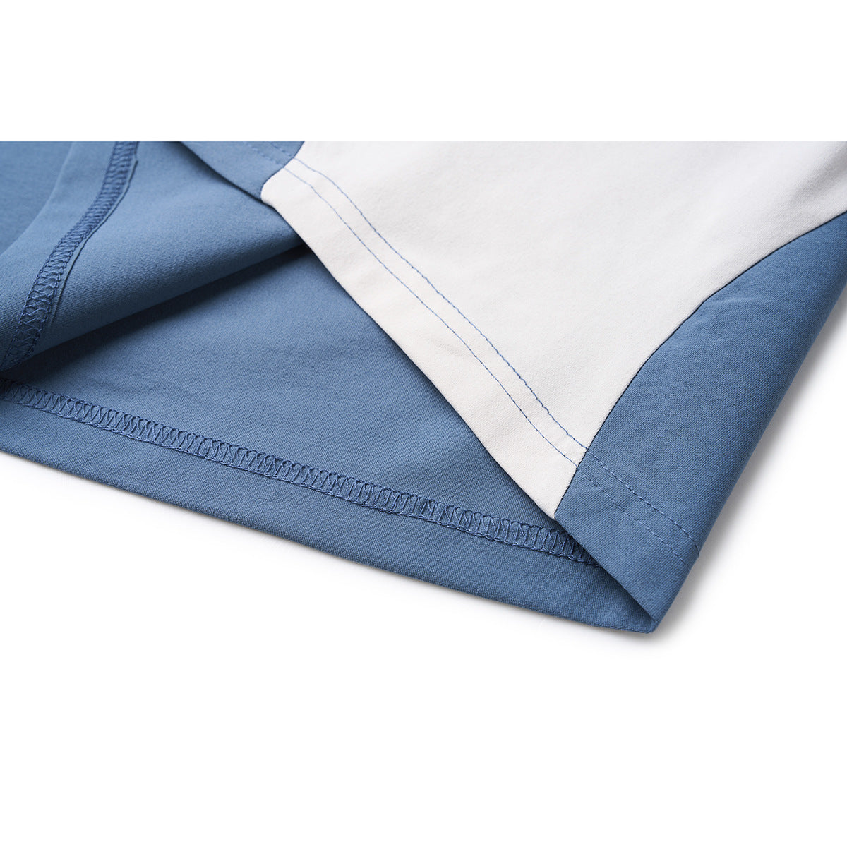 Close-up of a blue shirt hem and white side panel, showing overlock stitching and the finished edge.
