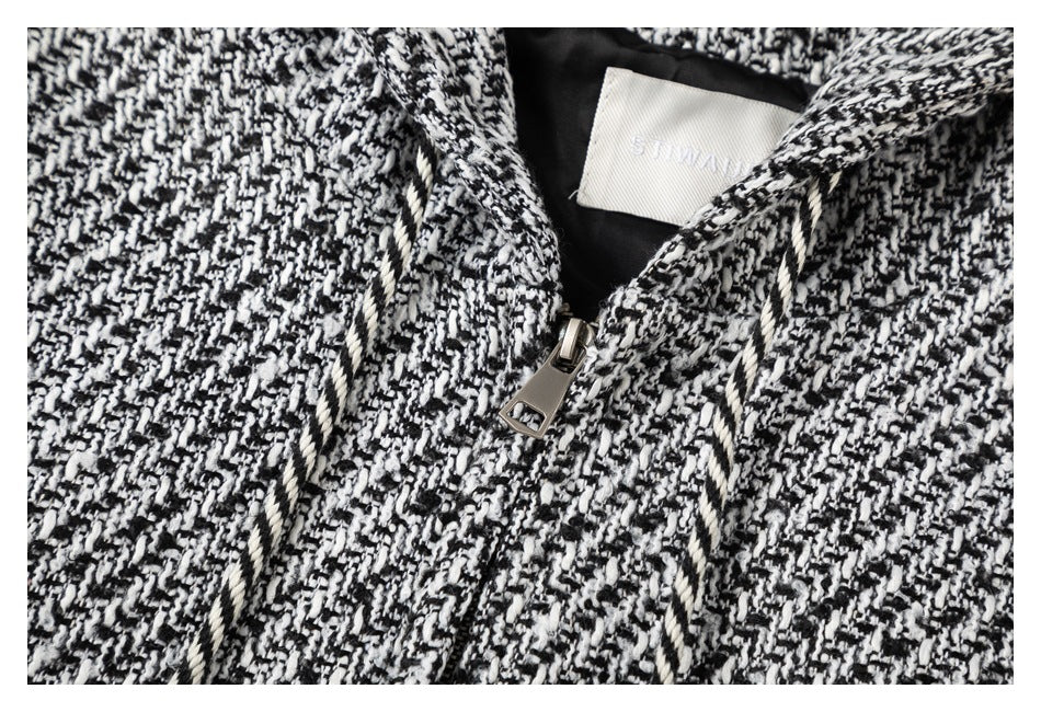 Close-up of the black-and-white patterned jacket's zipper, drawstrings, and sewn-in neck label.