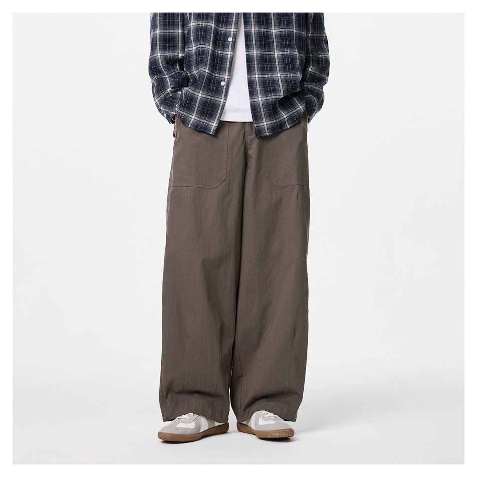 Model wearing brown wide-leg pants with patch pockets, plaid shirt and gray sneakers, front view