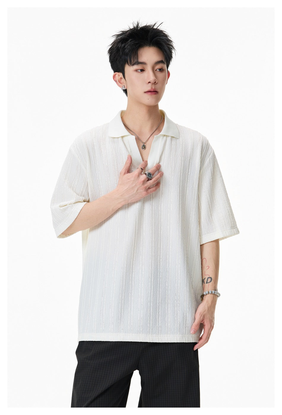 Closer view of a model wearing an ivory polo with a collar, open placket, and raised vertical texture.