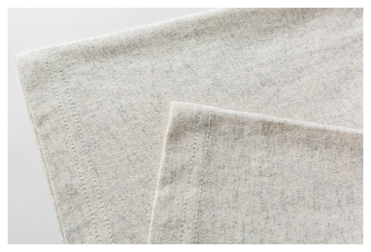 Close-up of a light gray heathered garment edge with parallel rows of stitching.