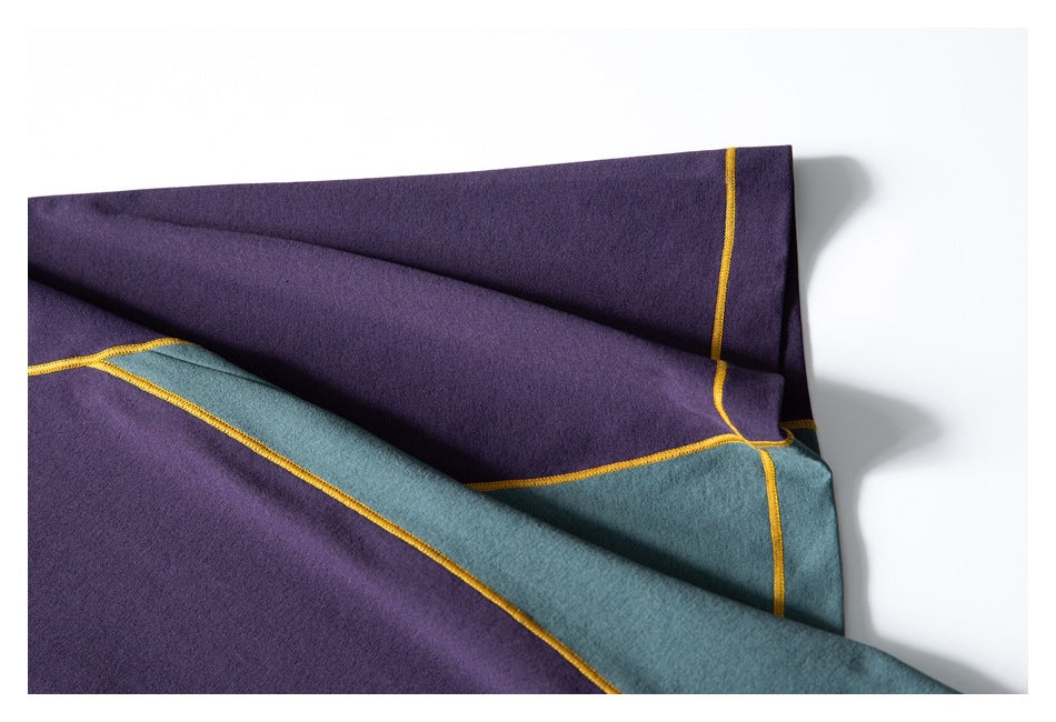Close-up of purple and teal T-shirt panels joined by yellow contrast stitching.
