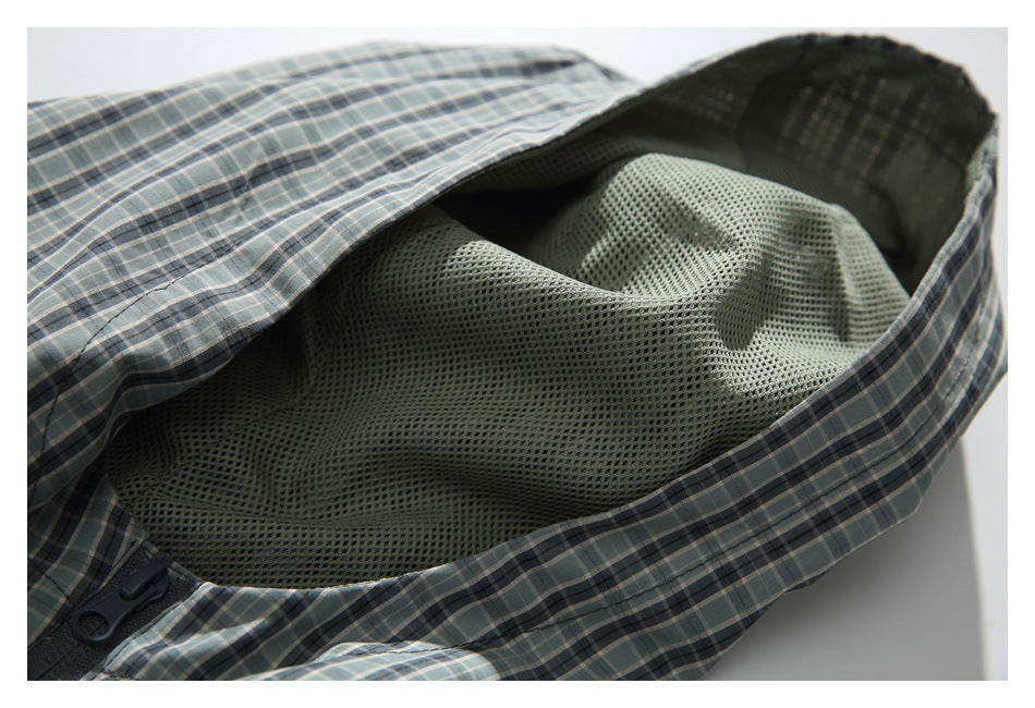 Close-up of blue-gray plaid garment opened to show light gray mesh lining and dark buttons.