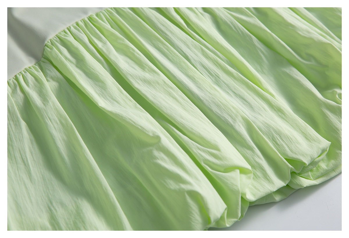 Close-up of the pale green skirt's gathered, pleated fabric and voluminous hem.