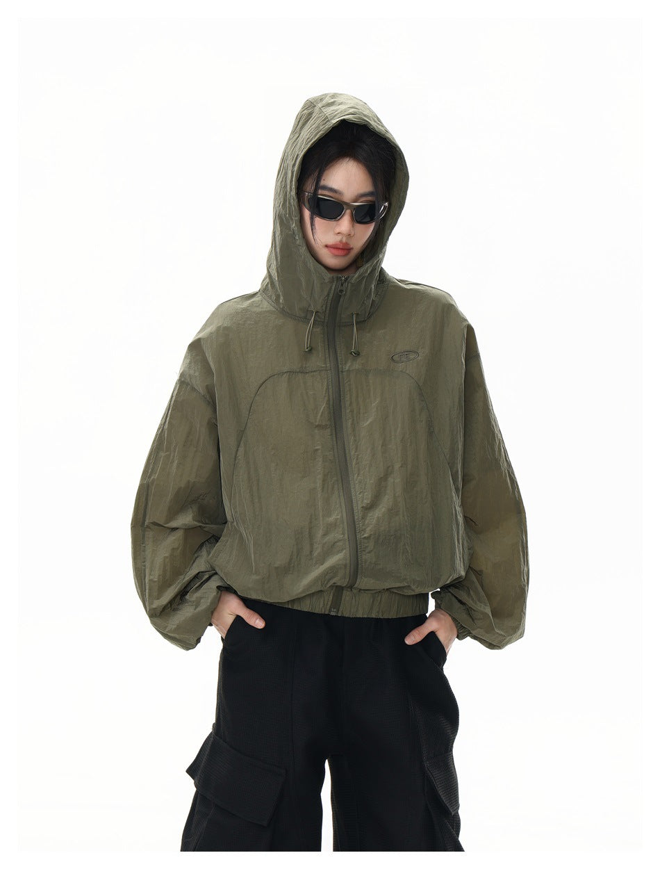 Model wearing an olive hooded jacket zipped up, with black cargo pants; front view with hood up.