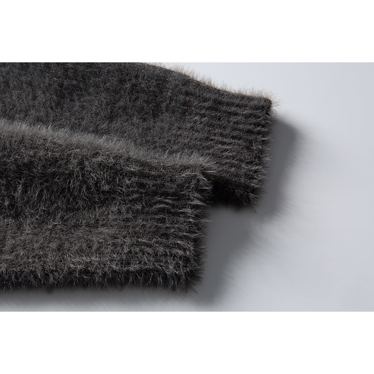 Close-up of the fuzzy charcoal-gray sweater sleeve and ribbed cuff.