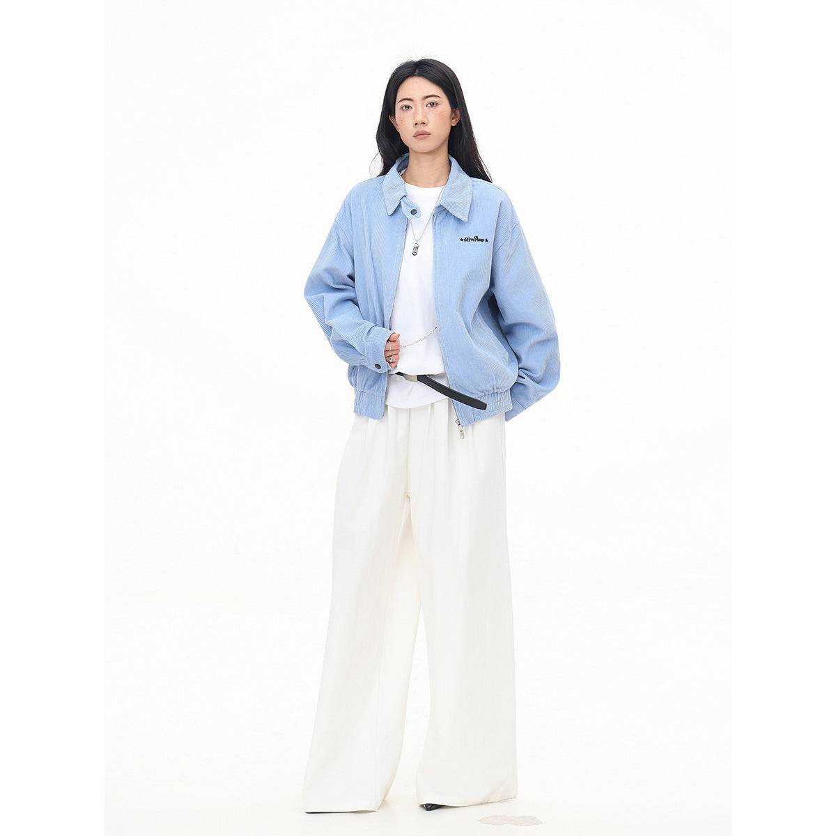 Model wearing a light blue collared zip jacket over a white top and wide-leg white trousers.