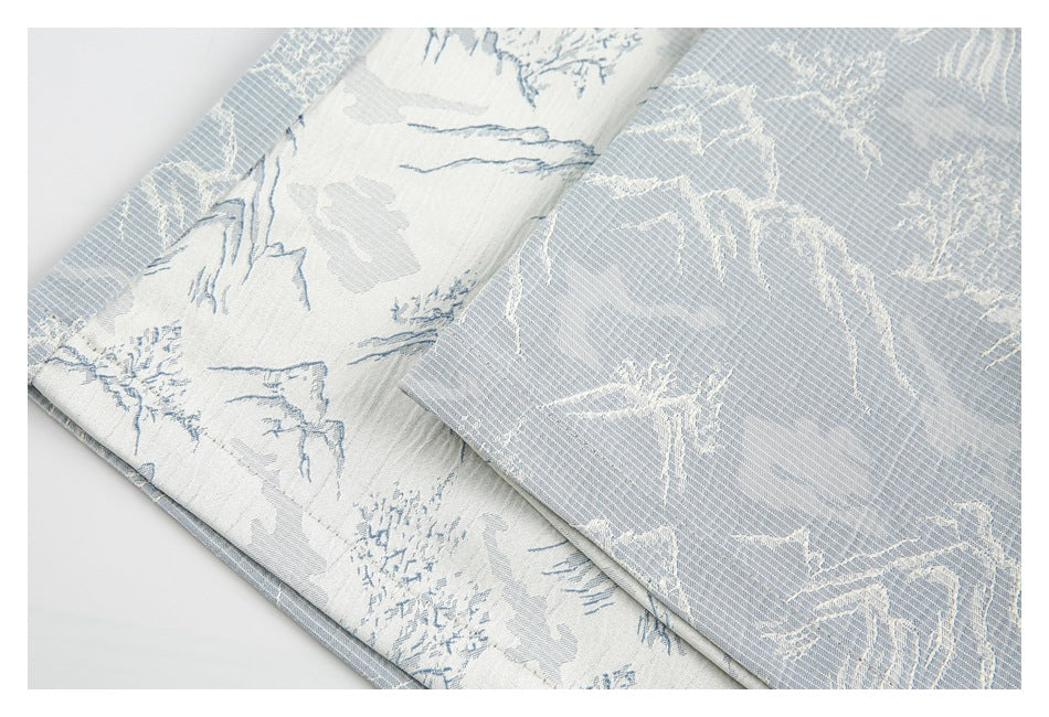 Close-up of the shorts' pale blue mountain-print fabric, showing a contrasting reverse side and folded edge.