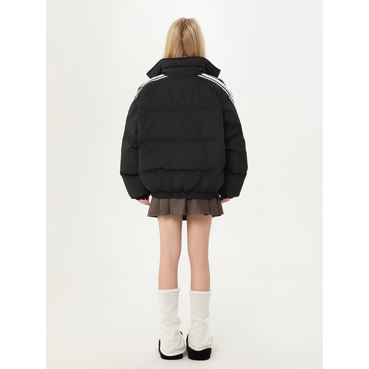 Back view of a black padded jacket with white shoulder stripes, worn by a model.