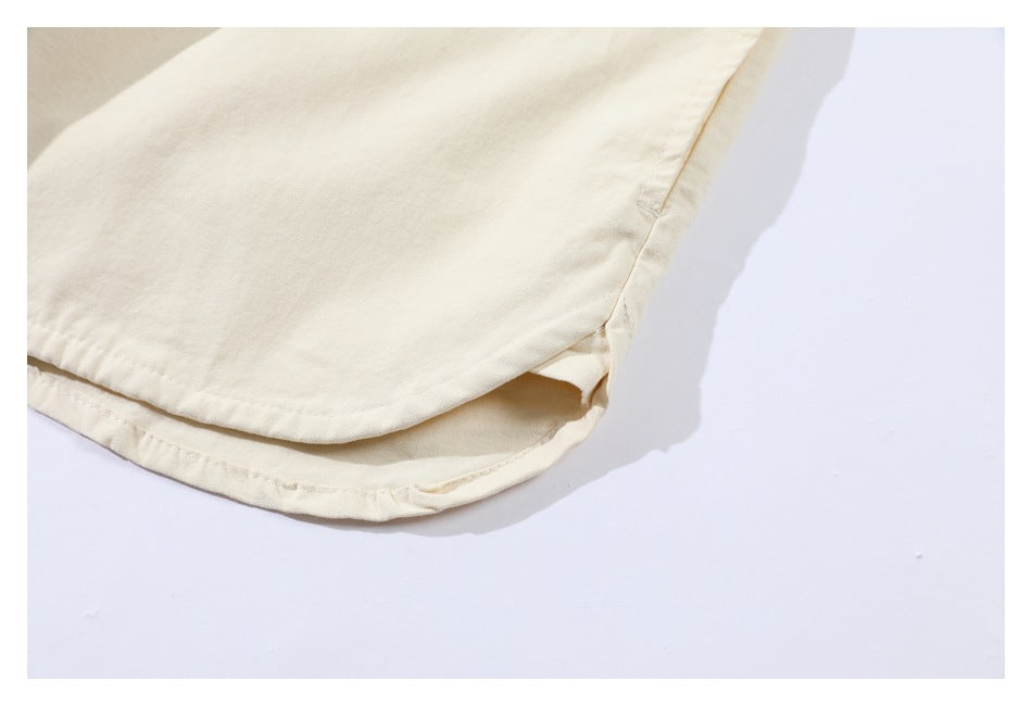 Close-up of the curved hem and side opening of an off-white garment.