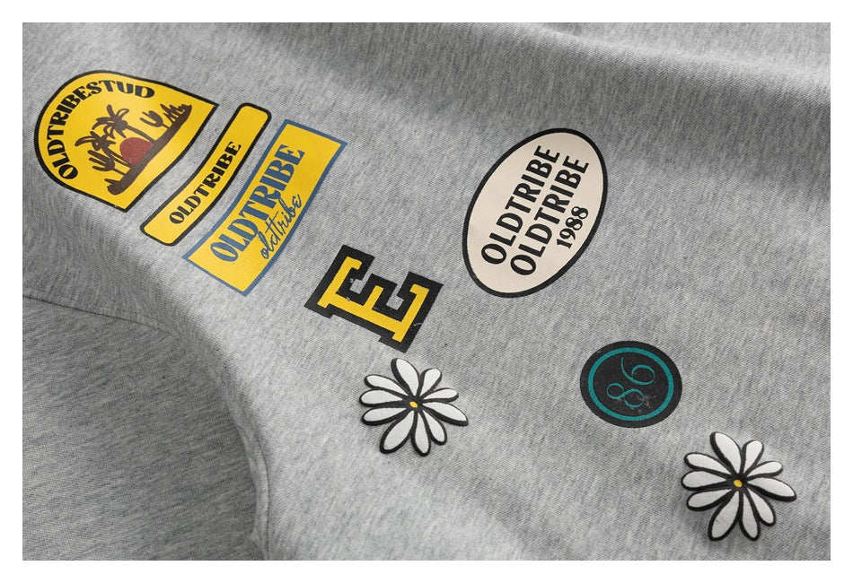 Close-up of assorted colorful Oldtribe-style patches and daisy motifs on heather-gray fabric.