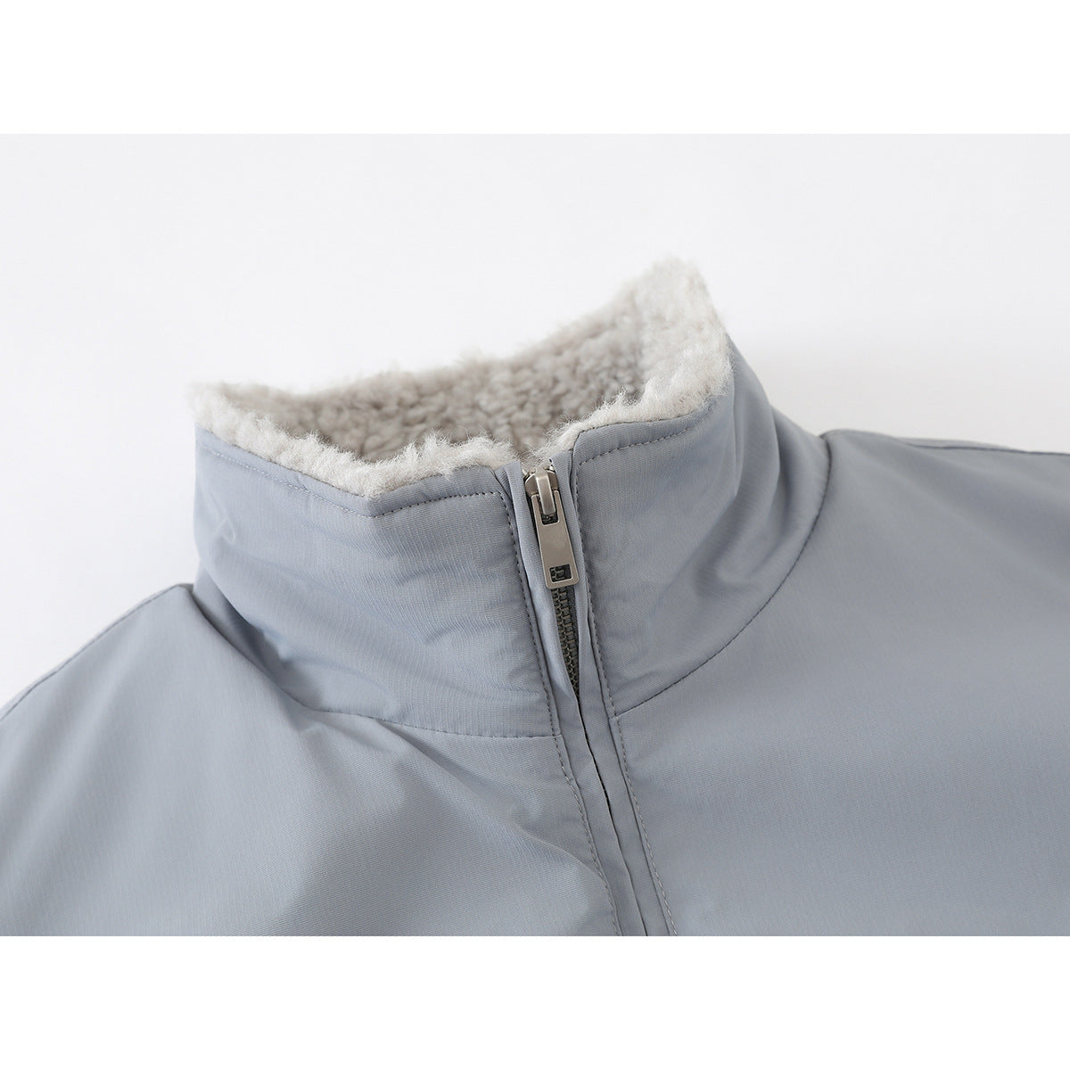 Close-up of a light gray jacket’s high collar, sherpa lining, and front zipper.