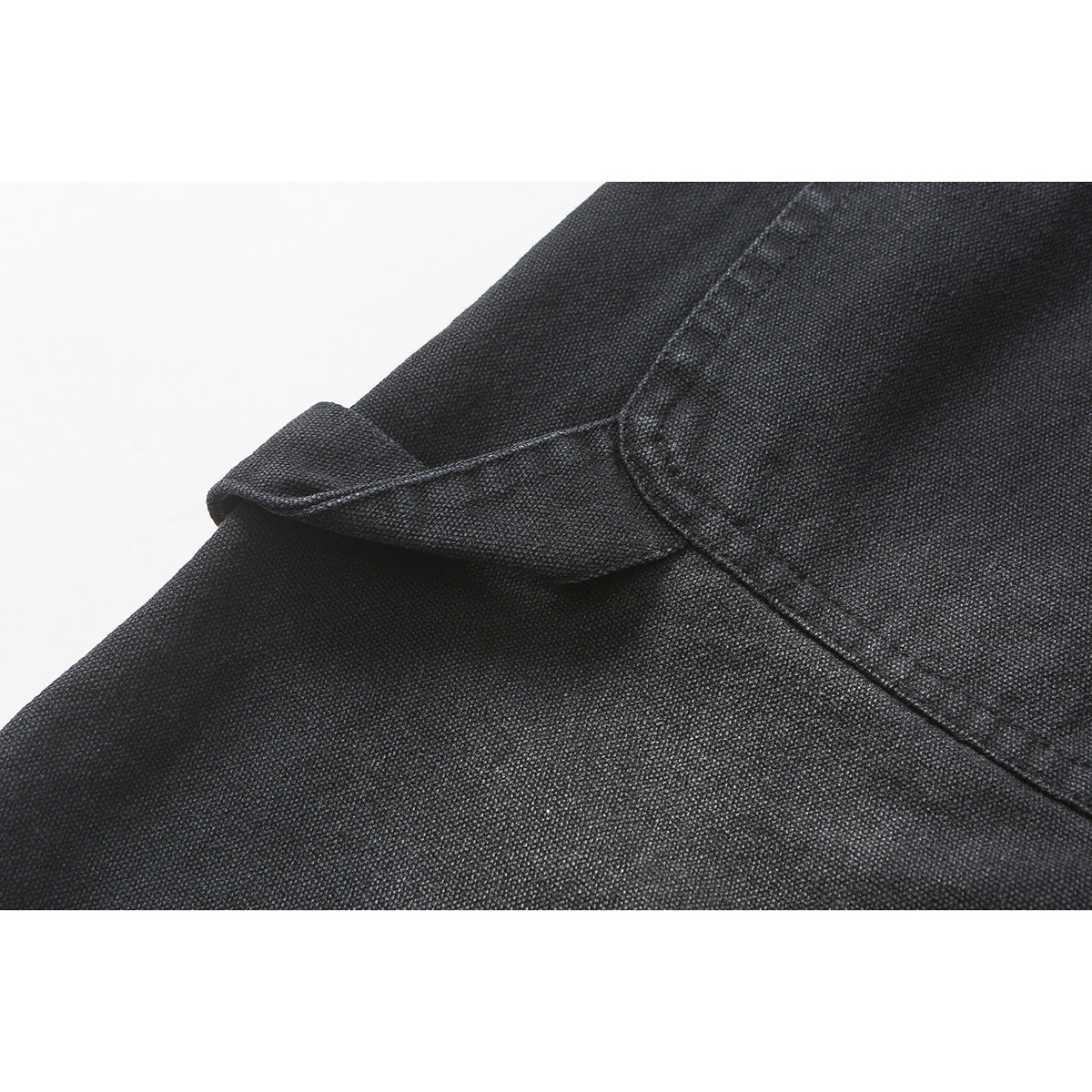 Close-up of dark textured shorts fabric and a folded pocket edge with visible stitching.