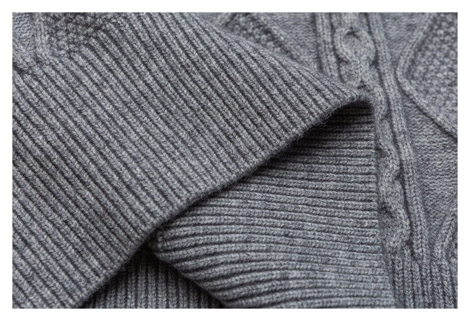Close-up of a gray knitted garment showing a wide ribbed edge overlapping textured knit.
