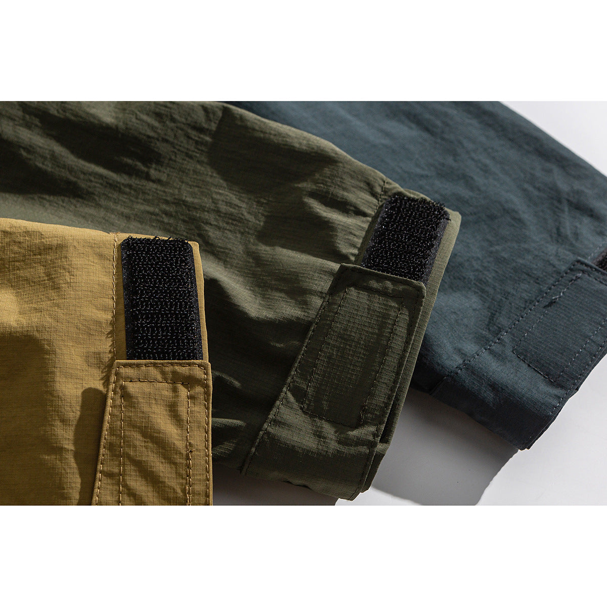 Close-up of adjustable hook-and-loop cuffs on tan, olive, and charcoal jackets.
