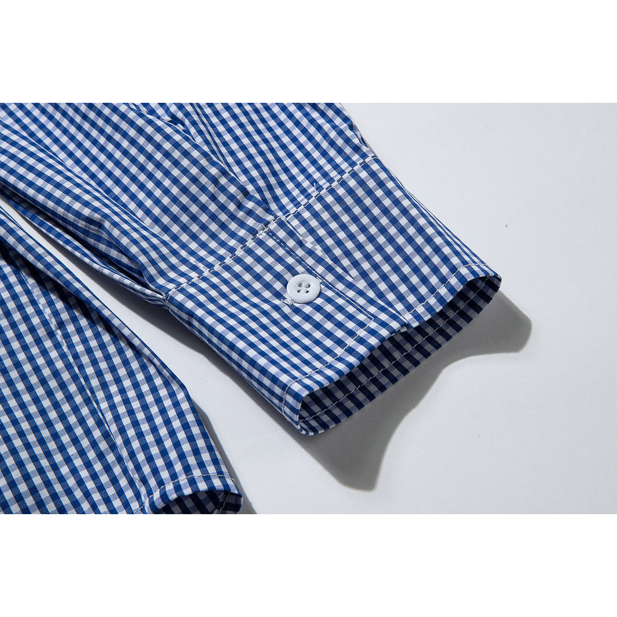 Close-up of a blue-and-white gingham shirt sleeve cuff with a white button.