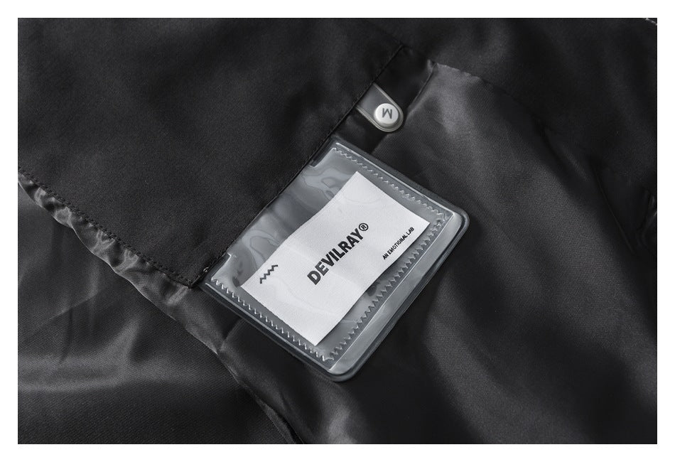 Close-up of a white DEVILRAY label inside a clear pocket on black garment fabric.