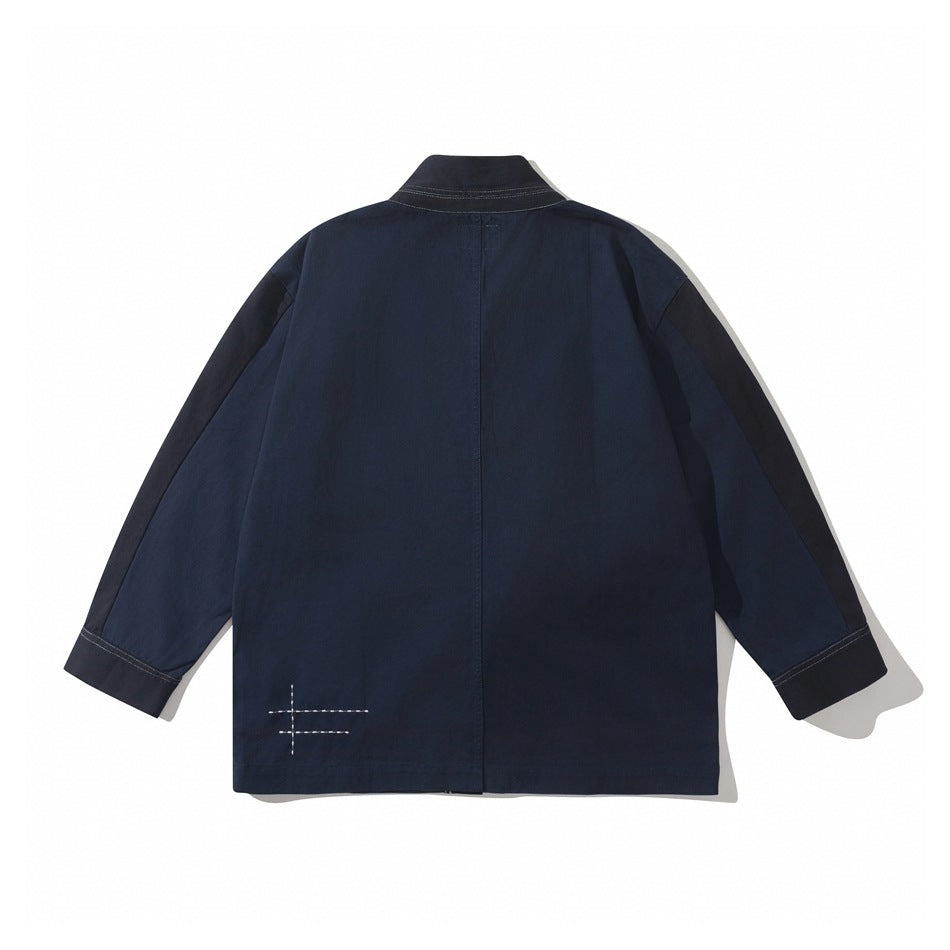 Back view of navy blue jacket with contrast sleeve panels, center back seam and white stitched cross detail