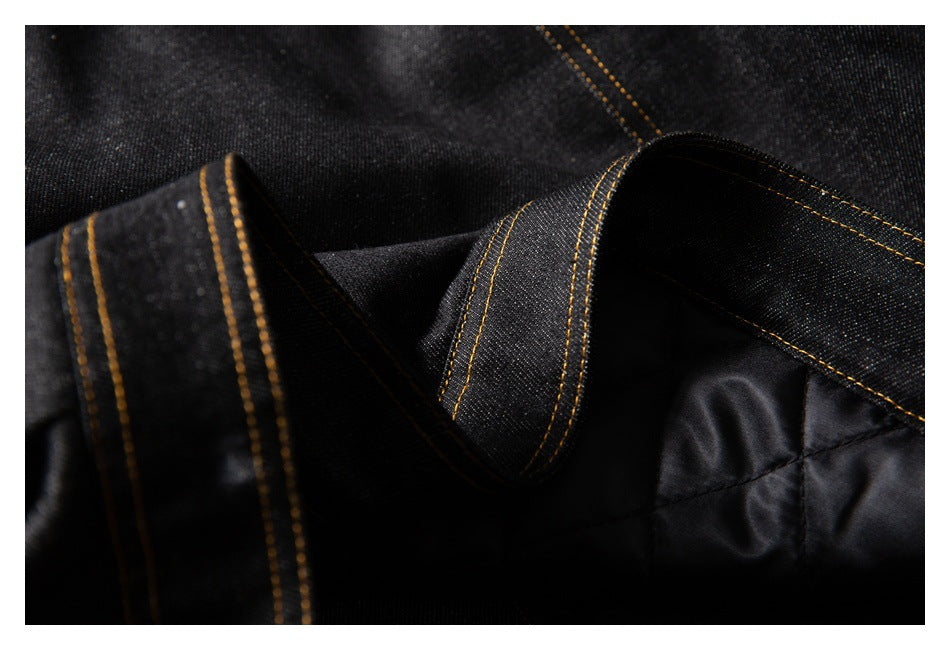 Close-up of the black denim jacket collar and dark inner lining with golden stitching.
