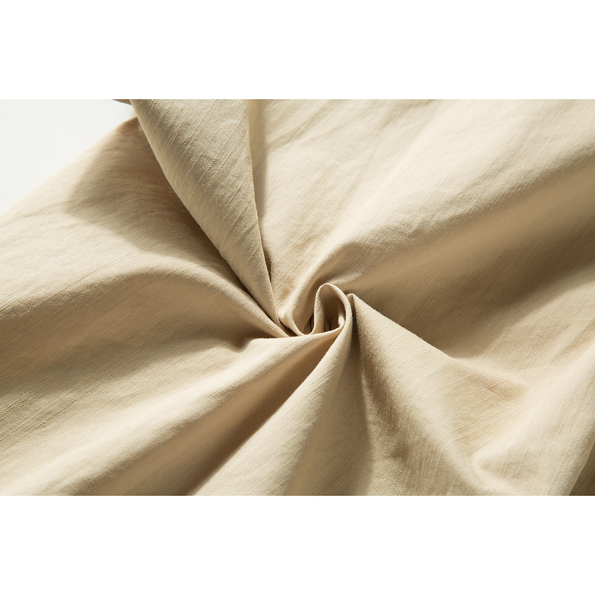 Close-up of beige shirt fabric gathered into folds, showing its surface and texture.