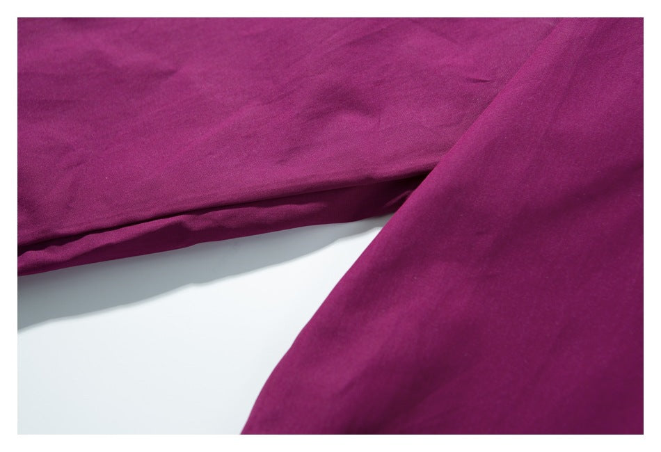 Close-up of deep magenta garment fabric with soft folds and a stitched edge.