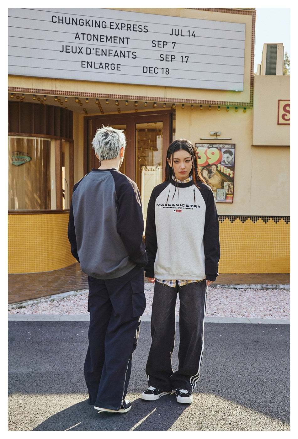 Two models pose in raglan sweatshirts; one shows the charcoal back, while the other faces forward in white and black.