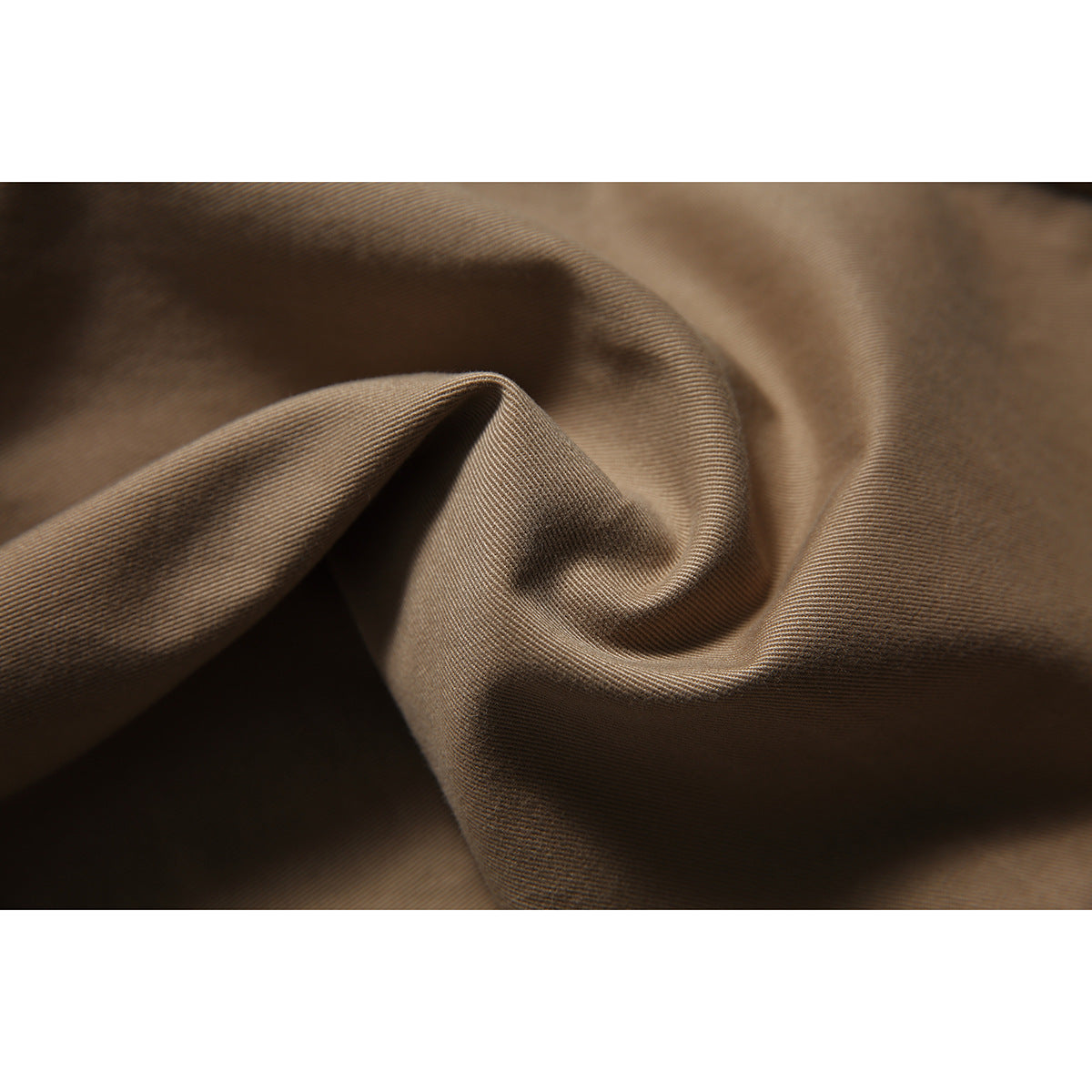 Macro view of brown trouser fabric draped to show its fine diagonal weave and texture.