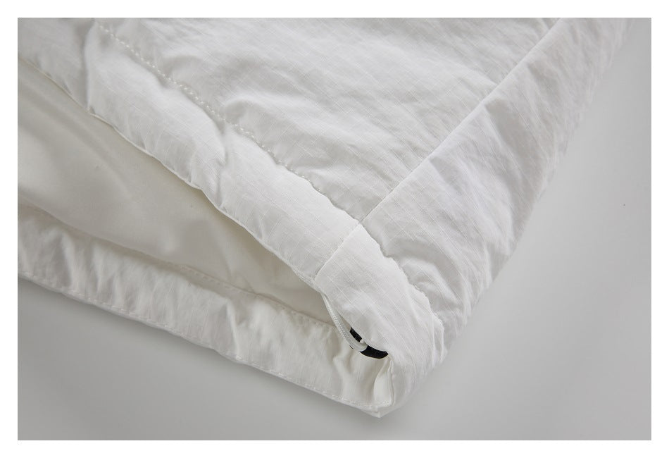 Close-up of a folded and stitched edge on a white garment, with a small black tab visible.