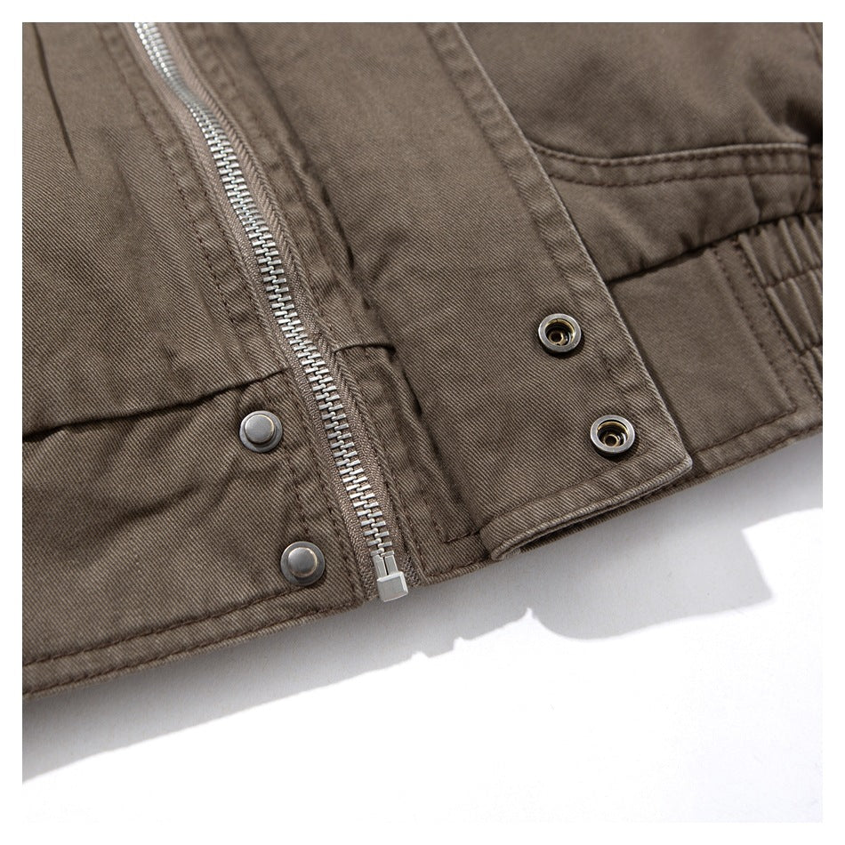 Close-up of a brown jacket hem with a silver zipper, snap fasteners, and gathered side seam.