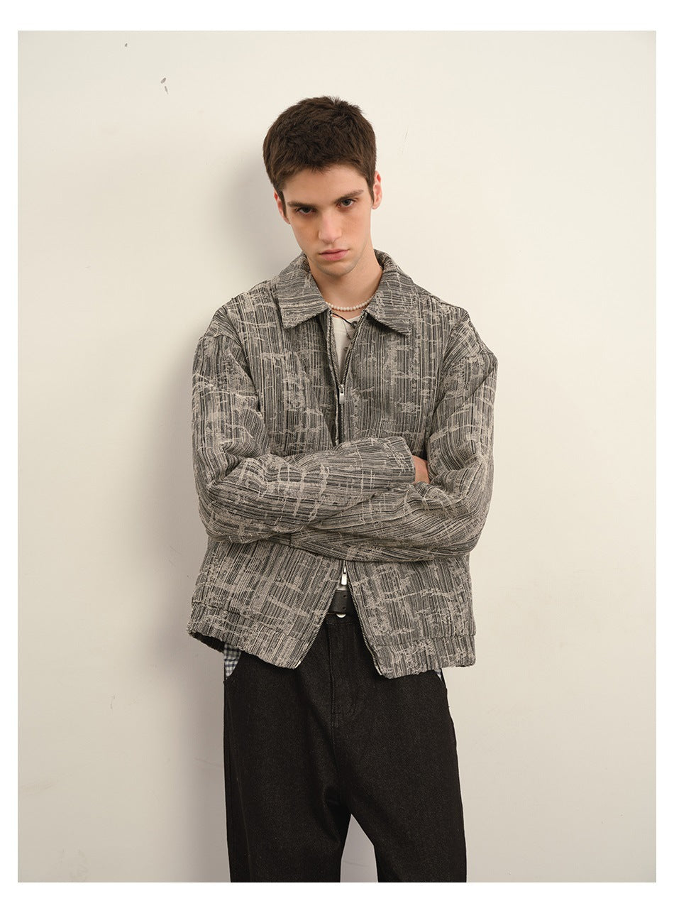 Closer view of a model wearing a gray abstract-patterned jacket, arms crossed over the front zipper.