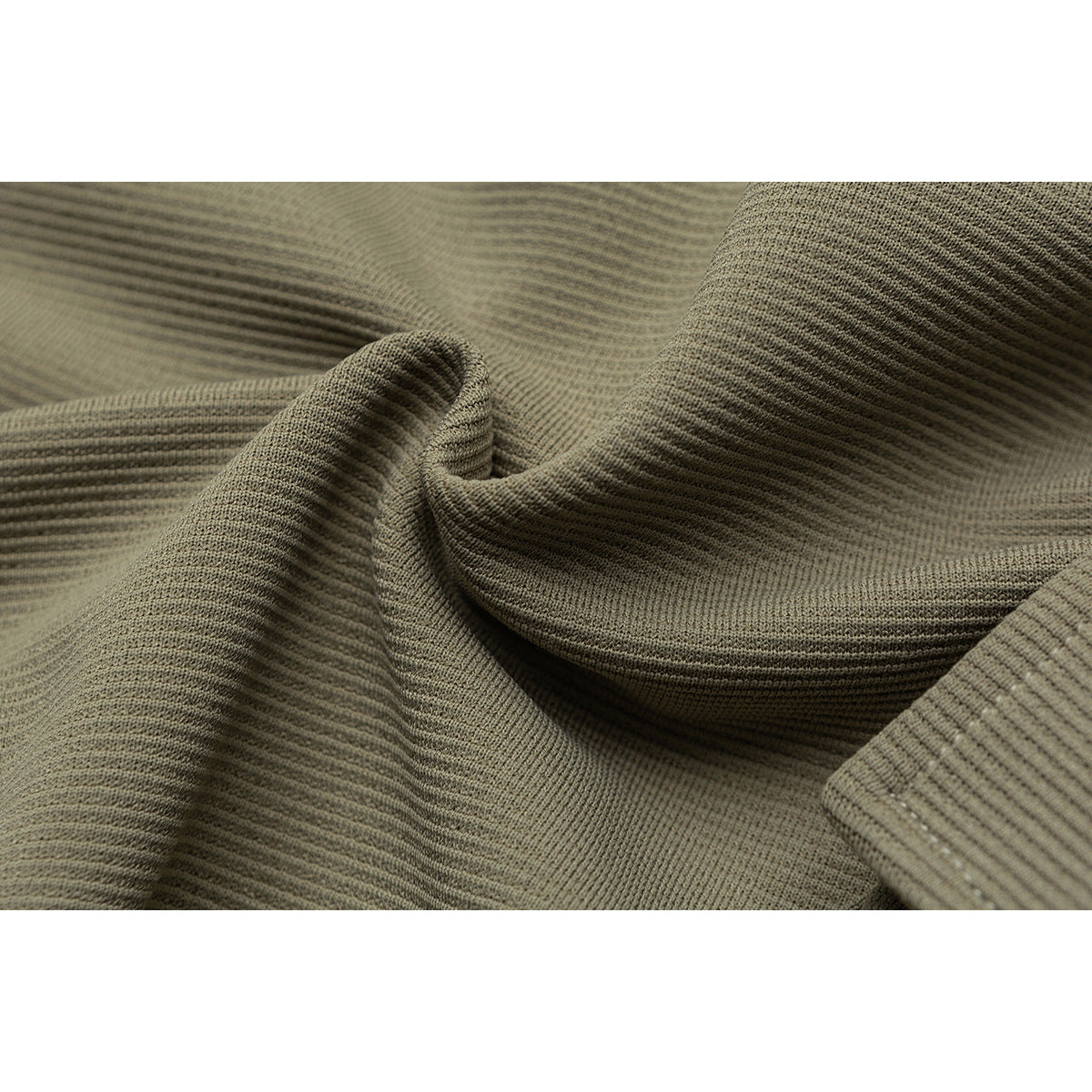 Macro view of the olive-khaki pants' textured fabric draped into folds.
