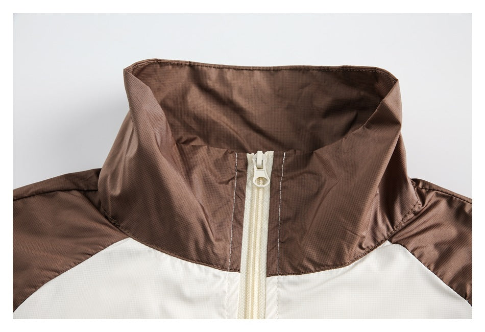 Close-up of a brown stand collar and cream front zipper on a color-block jacket.