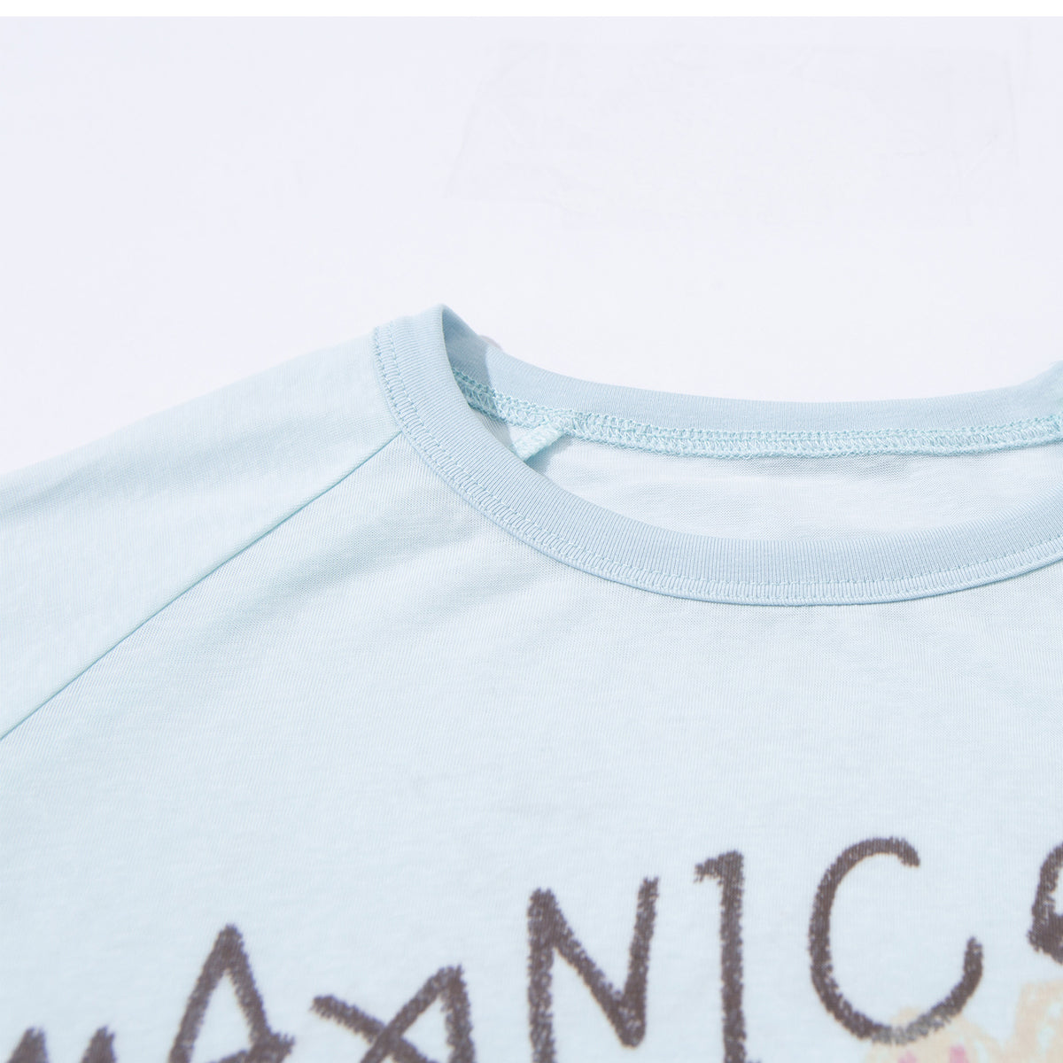 Close-up of a pale blue shirt's crew neckline and stitching, with part of its printed design visible.