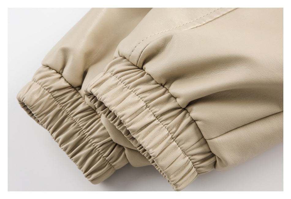 Close-up of beige trouser legs with gathered elastic cuffs and visible stitching.