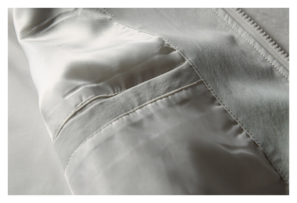 Close-up of pale gray jacket panel seams and stitching near the zipper.