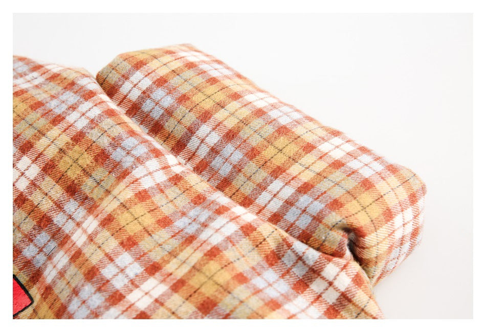 Close-up of folded orange, cream, pale blue and mustard plaid fabric.